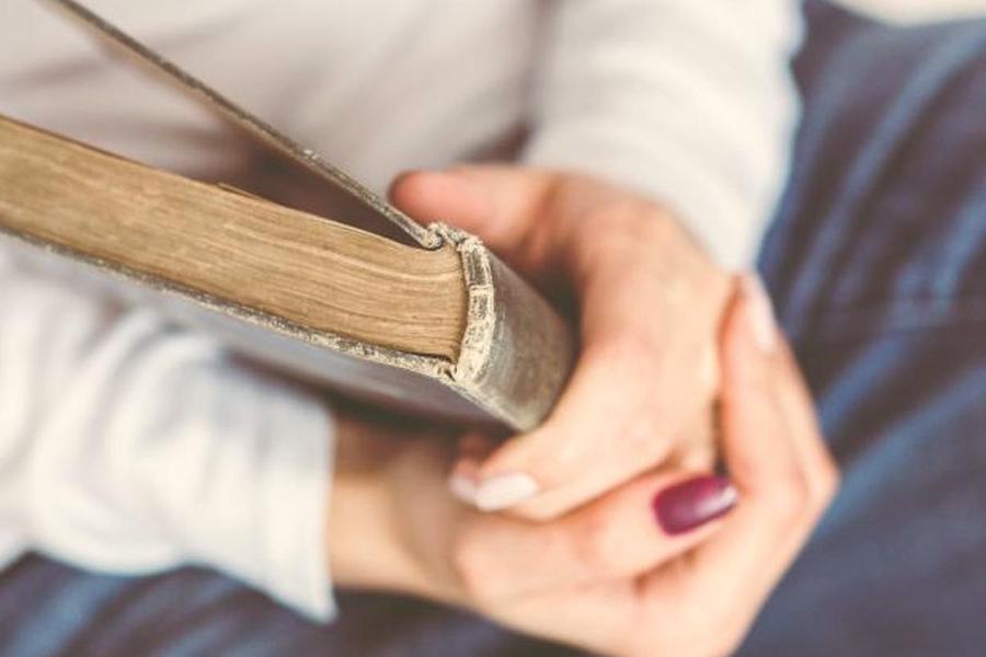 Twee handen die een oud boek vasthouden